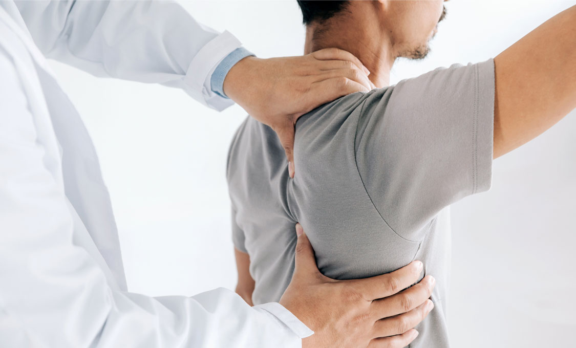 A doctor examining a patient's shoulder while the patient raises their arm.