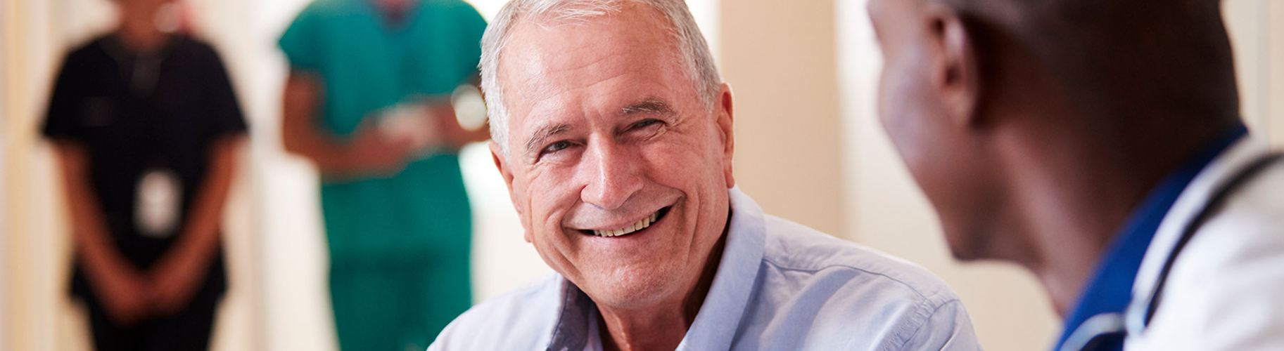 A smiling man speaks with a medical professional.