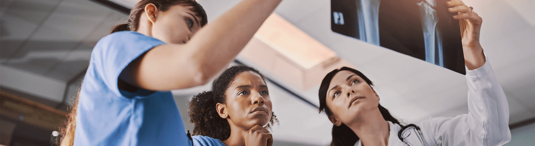 Three female medical professionals looking at an x-ray.