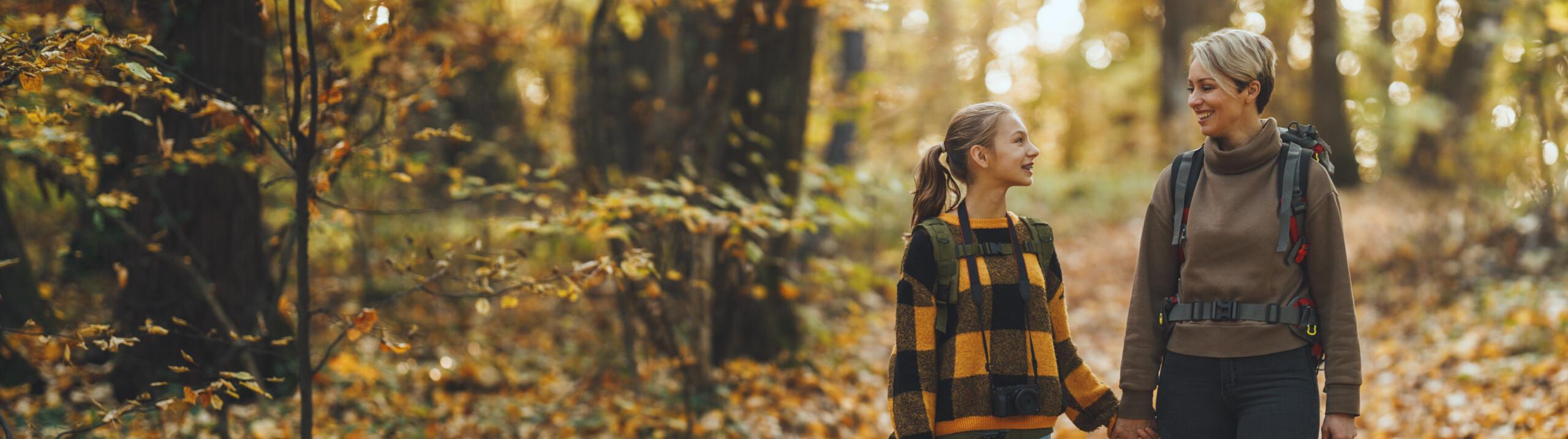 A woman and a child hiking in a forest.