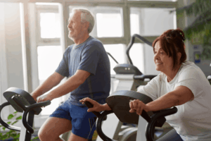 Two adults ride stationary bikes.