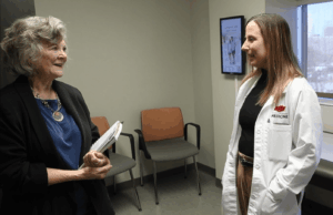 A woman speaks with a doctor in an examination room.
