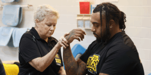 An osteopathic physician manipulates a patient athlete's wrist.