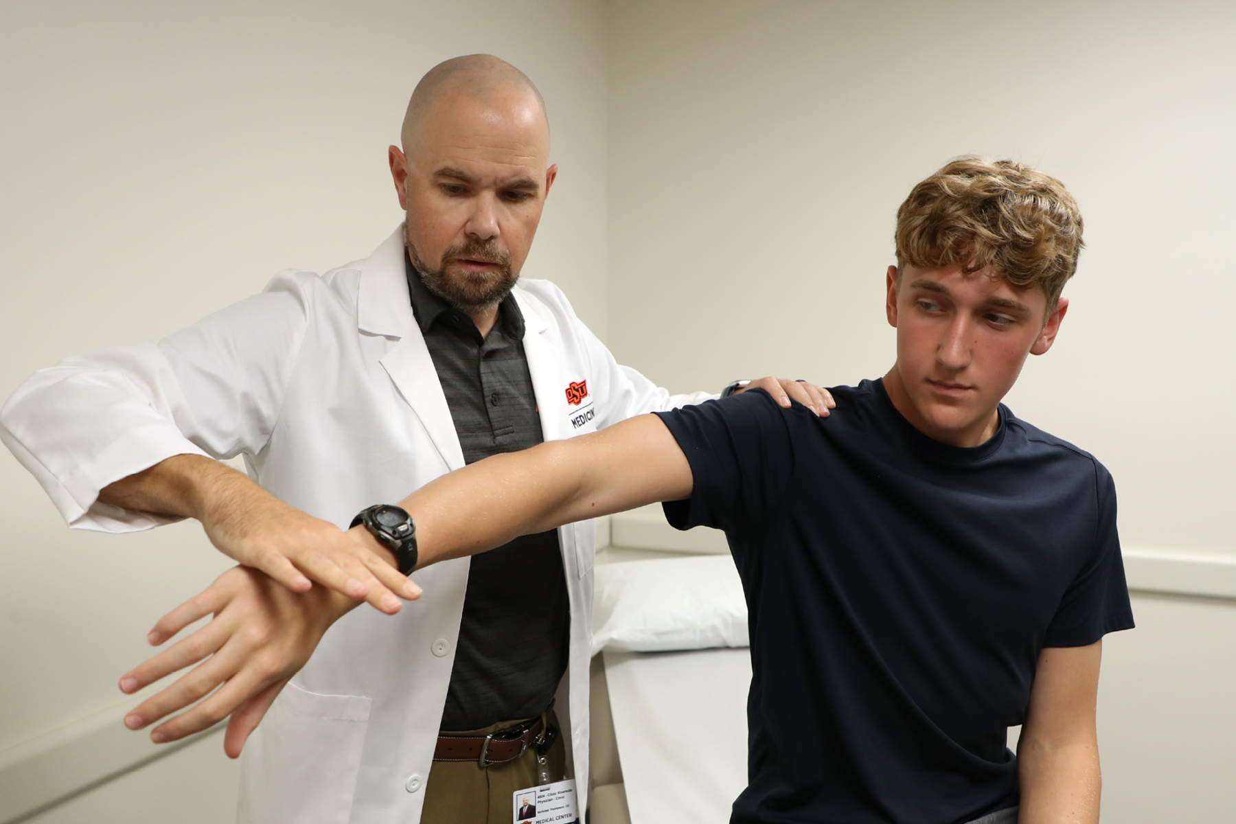 Photo of Dr. Nick Thompson evaluating a patient's arm in the Sports Medicine clinic.