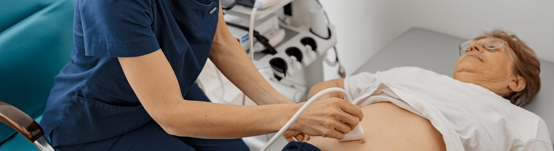 Doctor performing an ultrasound examine on senior patient abdomen at hospital.
