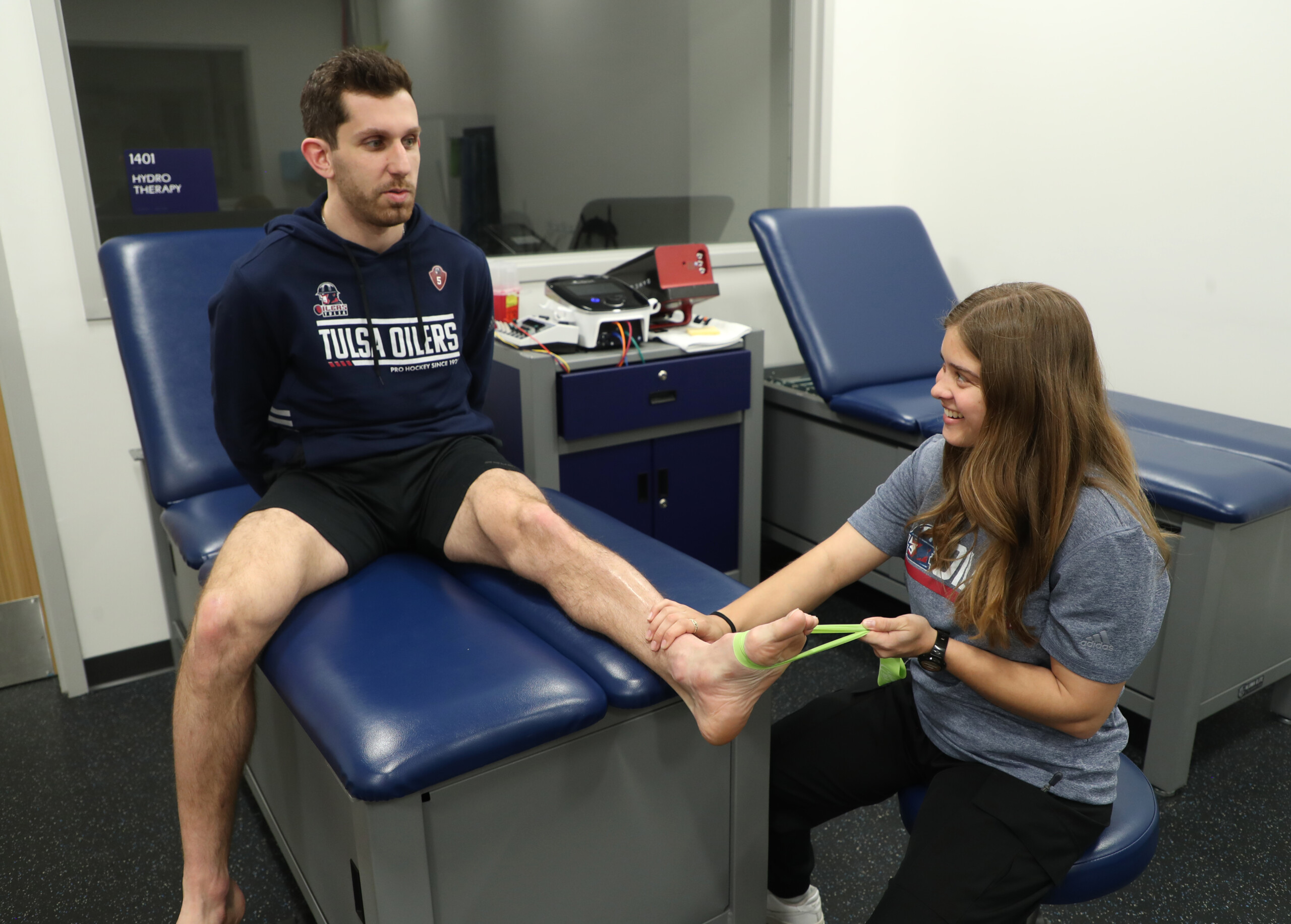 Dacie Sanders Athletic Training Athletic training student treats Tulsa Oilers hockey player with elastic band stretching of the lower leg.